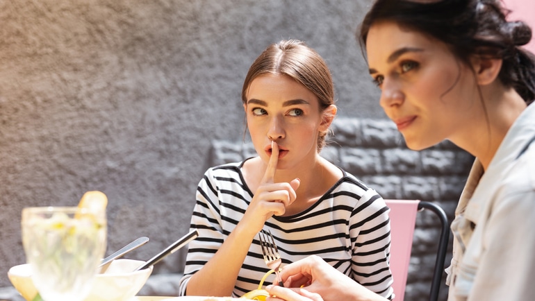 vrouw die fluistert over een diner en een streepje