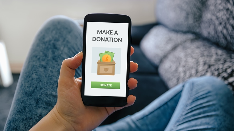 woman holding her smartphone with donation page open on the screen