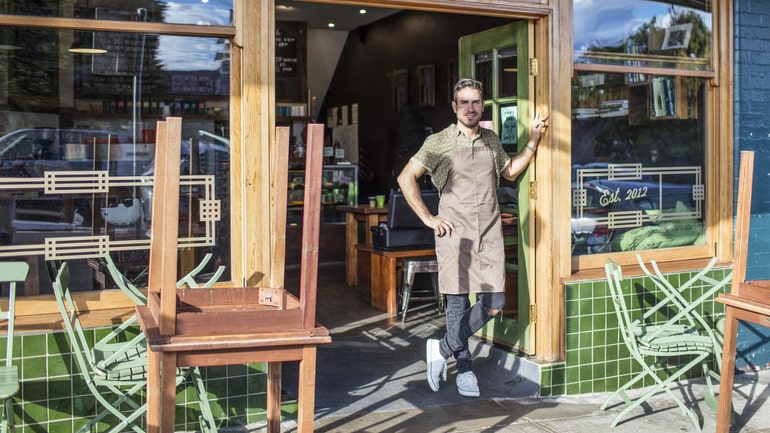 Coffee shop owner standing in front of a closed cafe