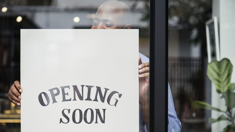 Man handing an "opening soon" sign in a restaurant